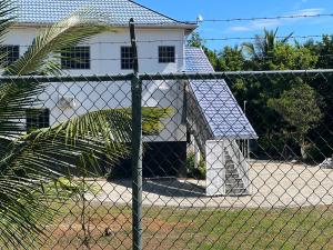 a white house behind a chain link fence at Thebreeze can accommodate up to 30 people 