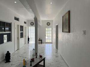 a hallway with white walls and a table and clocks at Thebreeze can accommodate up to 30 people 