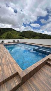 una piscina en la parte superior de un edificio con terraza de madera en Sítio com piscina incrível, en Santo Amaro da Imperatriz