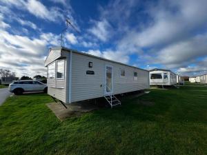 a small white tiny house on a grass field at Lovely 6 Berth Caravan At Cherry Tree Holiday Park, Ref 70403c in Great Yarmouth