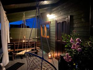 a porch of a house with a swing and flowers at Słoneczne Tarasy in Sasino