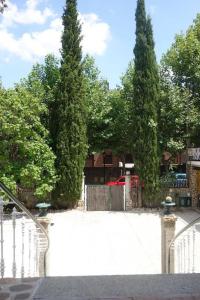 Ein weißer Zaun mit zwei hohen Bäumen im Hof. in der Unterkunft SUYOLUCE, su chalet en la Sierra in El Escorial