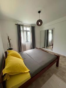 1 dormitorio con 1 cama grande con almohadas amarillas en Villa Montjoly, en Le Morne-Vert