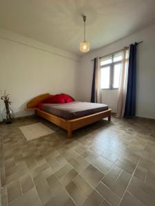1 dormitorio con 1 cama en una habitación con ventana en Villa Montjoly, en Le Morne-Vert