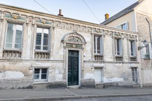 un antiguo edificio con una puerta verde en una calle en Appartement historique cœur de ville, chic et cosy, en Rambouillet