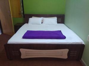 a bedroom with a large bed with a purple blanket at Hotel zamarrud palace in Jaipur