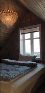 a bed in a room with a chandelier and a window at Cabin in Borgvåg Lofoten - Large in Straum