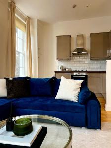 Stylish One Bedroom Apartment in the heart of Angel في لندن: أريكة زرقاء في غرفة المعيشة مع طاولة زجاجية