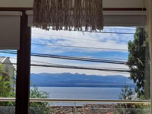 a window with a view of the water and mountains at LA TUA CASA in San Carlos de Bariloche
