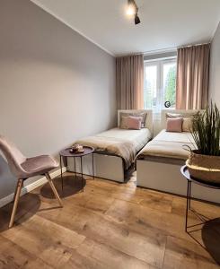 two beds in a room with a chair and a table at Apartament Przy Obserwatorium&Singielnia in Olsztyn