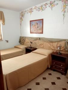 トッレ・ヴァードにあるAlloggio in Spiaggiaの花が飾られた壁の客室内のベッド2台