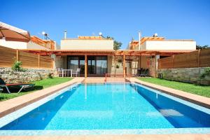a villa with a swimming pool in front of a house at Villa Lemonia Platanias in Platanias