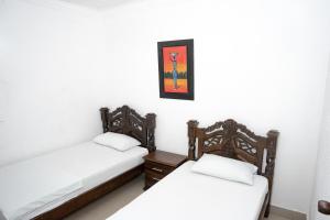 two twin beds in a room with white walls at Hotel La Casa Del Viajero in Cartagena de Indias