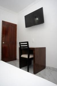 una scrivania con sedia e una TV appesa a un muro di Hotel La Casa Del Viajero a Cartagena de Indias