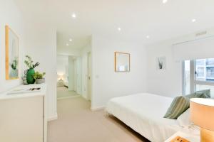 Habitación blanca con cama y ventana en Madison Hill - Clapham South 1 - Two bedroom flat, en Londres