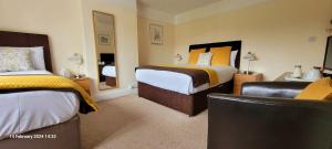 Hampton Lodge En-Suite Rooms with Free Parking في ستراتفورد أبون آفون: غرفة فندقية بسريرين وكرسي