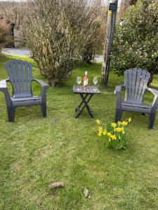 two chairs and a table in a yard with flowers at The Little Garden Hideaway with Stunning Sea Views and Garden in Holyhead