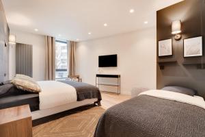 a bedroom with two beds and a flat screen tv at Appartement de Luxe 2BDR/7P - Louvre/tuileries in Paris