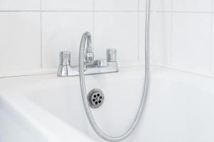 a shower with a hose and a shower head at Harborne 2 Bedroom House - Parking - Smart TV - Wifi - 62W in Birmingham