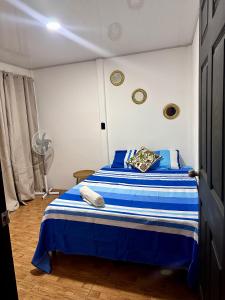 a bedroom with a blue and white bed with a fan at Casa caribes in Puerto Limón