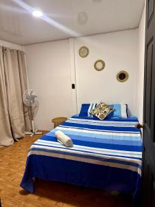 a bedroom with a blue and white bed with a fan at Casa caribes in Puerto Limón