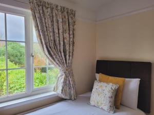 a bed in front of a window with a curtain at Hampton Lodge En-Suite Rooms with Free Parking in Stratford-upon-Avon
