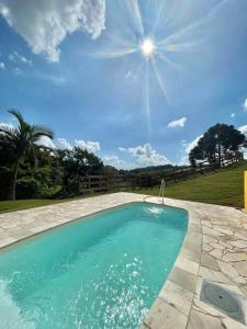 una piscina en un patio de piedra con el sol en el cielo en Casa de campo com piscina en Socorro