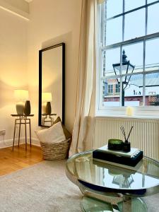 Stylish One Bedroom Apartment in the heart of Angel في لندن: غرفة معيشة مع طاولة زجاجية ونافذة