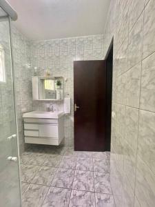 baño con lavabo, espejo y puerta en Casa de campo com piscina en Socorro