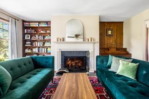 a living room with two green couches and a fireplace at Catskills Delaware River Modern Colonial Getaway in Narrowsburg