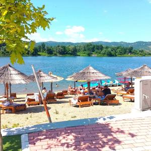 a beach with chairs and umbrellas and a body of water at Apartman Plaza 9 in Veliko Gradište