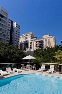 a swimming pool with chairs and an umbrella and some buildings at IPF2041 - Ipanema Tower Residence Service - Ipanema in Rio de Janeiro