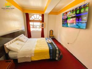 um quarto com uma cama e uma televisão na parede em Hotel Valery II em Huaraz