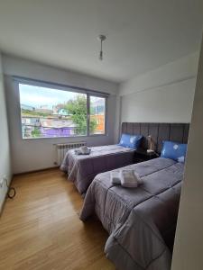 a bedroom with three beds and a large window at Belgrano Ushuaia in Ushuaia
