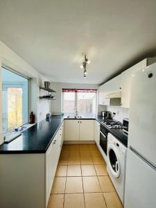 eine Küche mit weißen Schränken und schwarzen Arbeitsplatten in der Unterkunft Luna Cottage - Grove Road Cottages in Stratford-upon-Avon + 10 Fotos