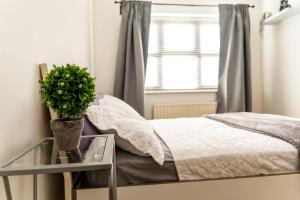 Un dormitorio con una cama y una mesa de cristal con una planta en Spacious 4 Bed Home in Milton Keynes -free parking en Milton Keynes