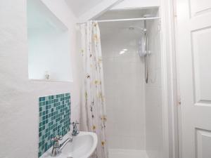 a white bathroom with a shower and a sink at Toadstools in Penryn