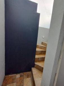 um corredor com uma porta preta e escadas numa casa em Departamento muy cómodo y muy bien ubicado. zona contry, pastora, estadio bbva em Monterrey