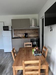 a kitchen with a wooden table with chairs and a refrigerator at Les jardins du Moiron in Le Champ-près-Froges