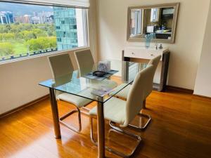 a glass table and chairs in a room with a window at Suite La Carolina QUITO in Quito