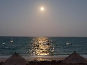 a beach with people in the ocean with the moon in the sky at Casa De Lua - Blue Paradise in Vilanculos