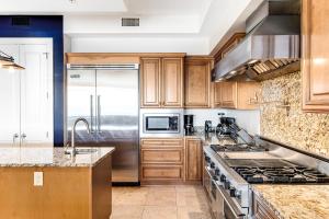 a kitchen with wooden cabinets and stainless steel appliances at Sanctuary by the Sea 3114 in Santa Rosa Beach