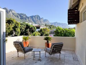 a balcony with two chairs and a table and mountains at Vetho Villa in Cape Town