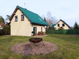 a house with a green roof and a grill in a yard at Zielona Zagroda in Borek