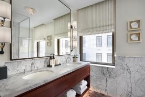 a bathroom with two sinks and a large mirror at The Wall Street Hotel New York City in New York