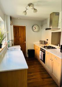 a kitchen with a counter and a clock on the wall at Bodhi Tree Cottage - Grove Road Cottages in Stratford-upon-Avon