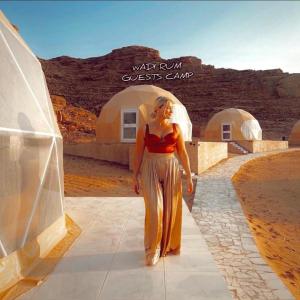 a woman is standing in front of a desert camp at rum guest house in Wadi Rum