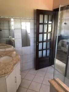a bathroom with a sink and a glass door at Pousada Encantos do Roncador in Barra do Garças