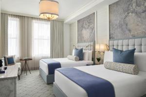 a hotel room with two beds and a desk at The Wall Street Hotel New York City in New York