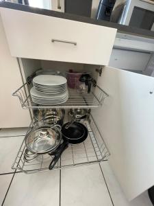 a shelf in a kitchen with plates and pans at TuS-FeWo#04 - Serviced & Executive Apartments in Mönchengladbach +16 photos